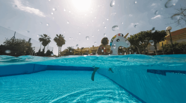 Niña jugando en piscina con flotador de unicornio