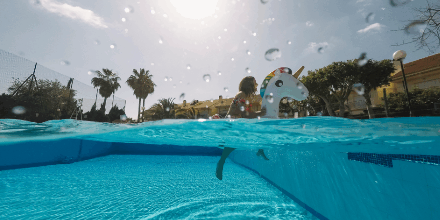 Niña jugando en piscina con flotador de unicornio