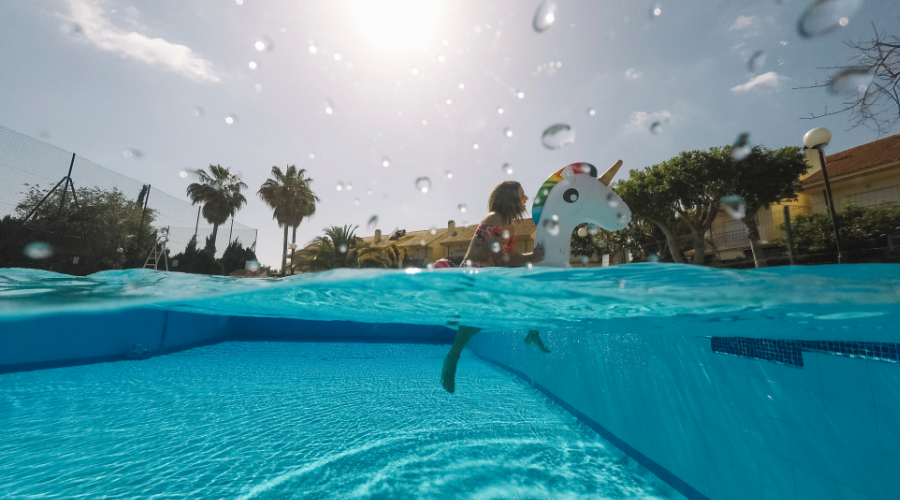 Niña jugando en piscina con flotador de unicornio